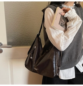 Detailed view of glossy dark leather hobo bag with zip pocket and fashion inscription