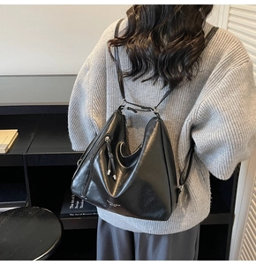 Detail of minimalist black faux leather hobo backpack featuring silver zippers and hardware