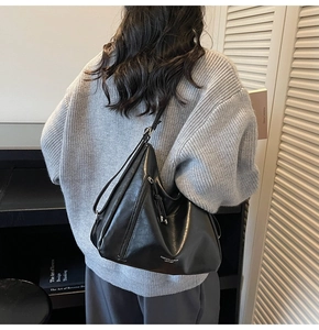 Detail of black leather shoulder bag with irregular folds and tassel decoration