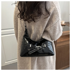 Detail of black glossy patent leather hobo bag with silver buckle and metallic eyelets