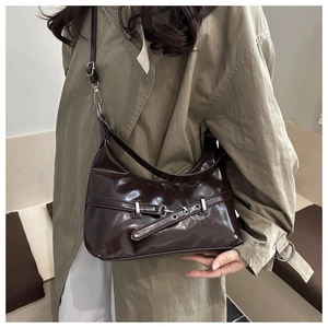 Detail of dark brown glossy leather underarm bag with silver metallic buckle detail