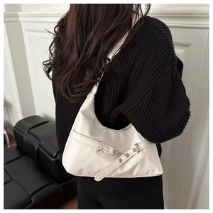 Close-up of a white crescent underarm bag with metal buckle detail and smooth leather finish