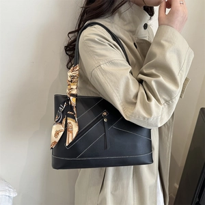 Black leather tote bag with contrast stitching and silk scarf accessory on a model
