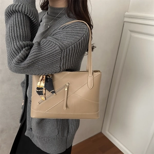 Elegant khaki tote bag with decorative silk scarf shown on shoulder in casual style