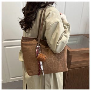 Detail showing the leopard print suede tote bag texture with a plush bear charm accessory