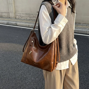 Brown vintage oil wax leather tote bag with tassels shown in an outdoor street style