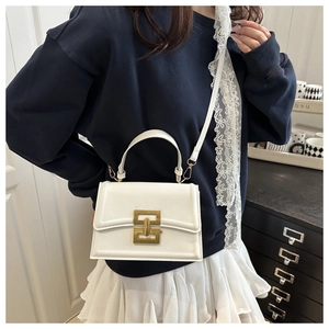 Detail of white leather crossbody bag with gold geometric buckle worn by a female model