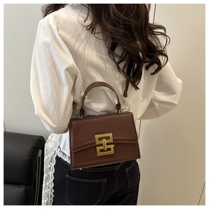 Rear view of brown leather crossbody bag with gold lock buckle on model's shoulder