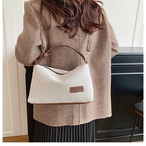 Detail of grey knitted crossbody bag featuring brown leather trim and shoulder strap
