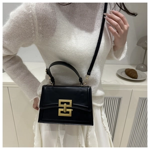 Detailed close-up of a black leather handbag with a signature gold geometric metal lock