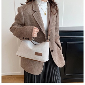 Retro beige canvas handbag with brown leather trim styled on a herringbone blazer