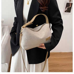 Detail of cream fabric shoulder bag featuring brown leather trim and shoulder straps