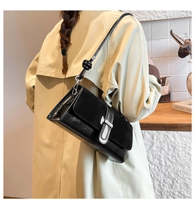 Detail of black leather shoulder bag with silver buckle and knotted strap on model