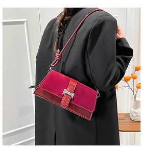 Detail of burgundy shoulder bag featuring matte suede texture and silver buckle finish