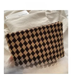Close-up of houndstooth weave texture and brown jacquard fabric on stylish clutch bag