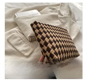 Detail of premium houndstooth makeup bag in brown wool fabric held by a model
