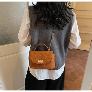 Sac matelassé marron orange avec fermoir doré porté par un mannequin en intérieur