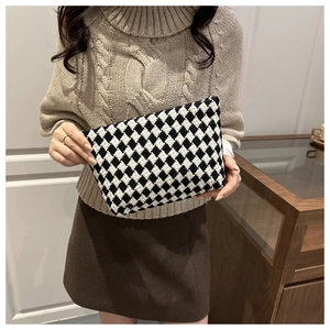 Macro shot of the woven black and white checkered clutch bag with 3D texture and zipper