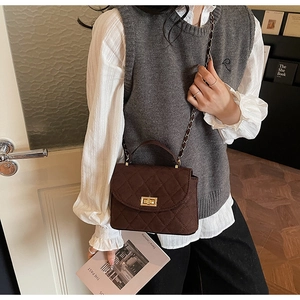 Detail of dark brown quilted chain bag with gold twist lock and velvet suede texture
