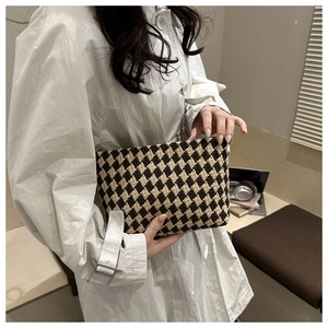 Macro shot of diamond lattice tweed clutch bag held against a white coat background