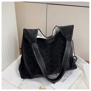 Detailed shot of a black tote bag with white contrast stitching on a vintage leather texture