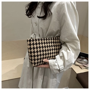 Detail view of a vintage rhombus woven clutch bag featuring brown and beige fabric texture