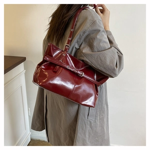 Close-up of deep red patent leather shoulder bag showing glossy mirror-like finish