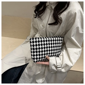 Detailed close-up of a black and white checkered knit clutch bag with textured fabric