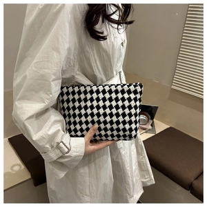 Detail of checkered knit handbag held by a woman in a beige trench coat