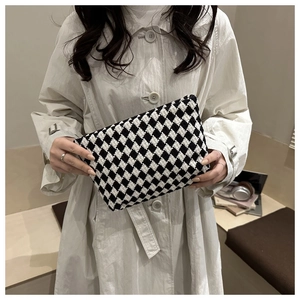Detail of a chic black and white checkered wool clutch with a side metal buckle closure