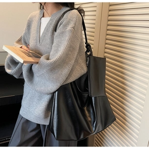 Detail of a black leather tote bag with a small pouch and knotted strap design