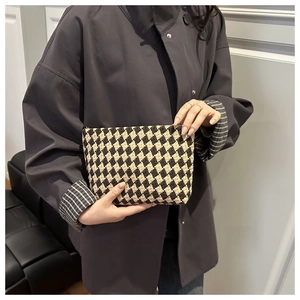 Detail of hand-held quilted diamond pattern knit pouch in black and white texture