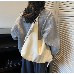 Close-up of a cream white leather tote bag with a unique knotted shoulder strap detail