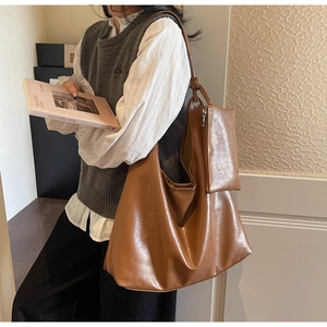 Detail of a large brown textured leather tote bag with a small matching zip pouch charm