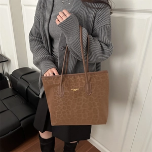 Brown leopard print suede tote bag with golden logo carried by model in casual outfit