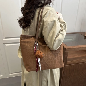 Vintage brown leopard print tote bag with plush bear charm worn over the shoulder