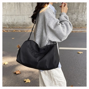 Close-up of black nylon gym bag featuring spacious zipped pockets and wide shoulder strap