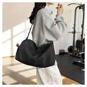 Side view of large black waterproof gym bag on model in a sunny fitness studio