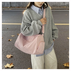 Lifestyle shot of a pink nylon crossbody pillow bag showing adjustable strap and zipper details