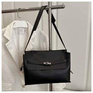 Close-up of minimalist black leather square bag featuring silver twist-lock and matte finish