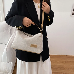 Chic beige canvas tote bag with brown leather trim and adjustable crossbody strap