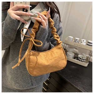 Détail d'un sac à main marron en daim avec une poignée plissée et un nœud décoratif chic