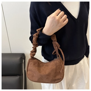 Détail d'un sac demi-lune en velours côtelé marron avec anse chouchou et fermeture éclair
