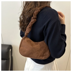Détail d'un sac porté épaule en daim marron avec une bandoulière plissée style chouchou
