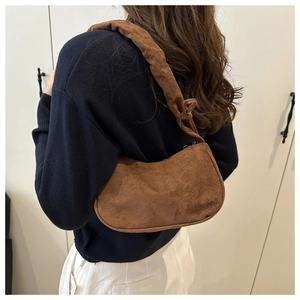 Détail du sac de bras en daim marron foncé avec bandoulière nouée sur modèle