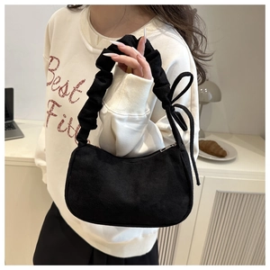Détail d'un sac en velours noir avec poignée plissée et décoration de nœud élégante