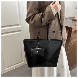 Detail of minimalist black glossy tote bag with matching pouch shown on shoulder