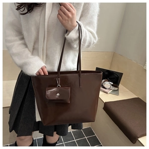 Detail of chocolate brown tote bag showing smooth leather texture and matching small pouch
