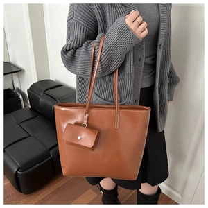 Close-up of a brown tote bag with premium leather texture and matching mini coin purse detail