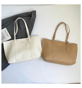 Close-up of cream and khaki tote bags with vertical stitching and long shoulder straps